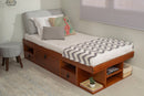 foto ambientada cama solteiro com gavetas bali caramelo vista de lado com colchas travesseiros e almofadas em cima da cama
