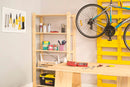 estante de madeira legno completa cru em garagem com objetos sobre as prateleiras e pallet na parede com bicicleta