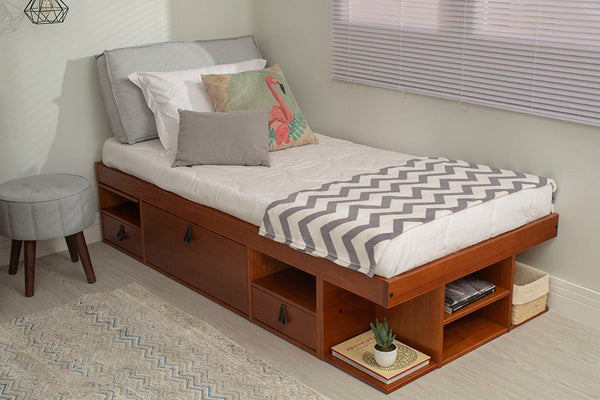 foto ambientada cama solteiro com gavetas bali caramelo vista de lado com colchas travesseiros e almofadas em cima da cama