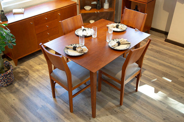 foto ambientada da mesa de jantar 4 lugares lotus caramelo em sala de jantar vista de cima com loucas sobre o tampo e 4 cadeiras estofadas lotus envolta
