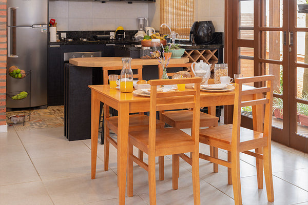 foto ambientada da mesa de madeira jantar 4 lugares ape nozes em cozinha vista na diagonal com loucas sobre o tampo e 4 cadeiras ape nozes