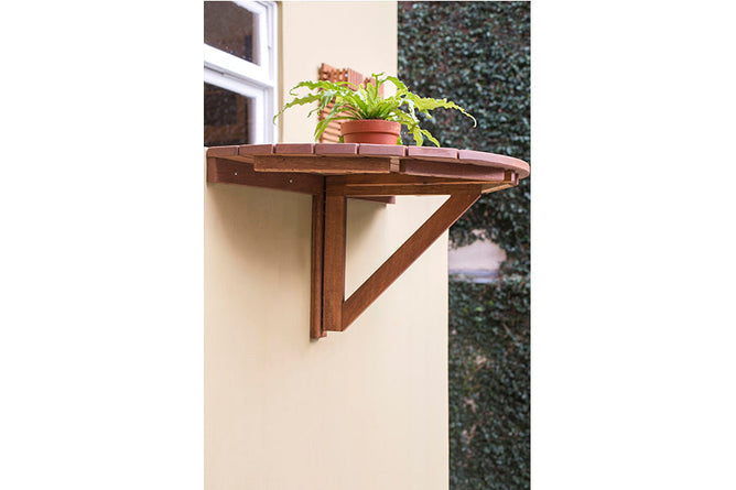 foto ambientada da mesa rustica redonda dobravel legno jatoba vista debaixo fixada na parede com planta sobre ela