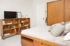 foto ambientada das 2 estantes para quarto charme doce de leite escovado com objetos e tv sobre a estante