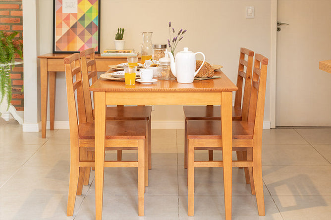 foto ambientada da mesa de madeira apê nozes com 4 cadeiras em sala de jantar com louças sobre o tampo