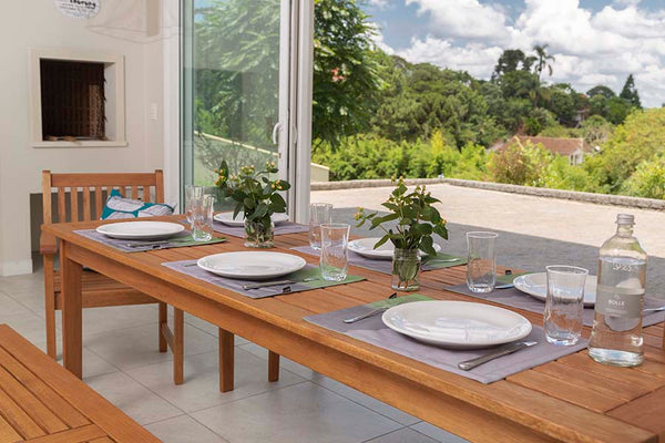 foto ambientada em churrasqueiro da mesa rustica de madeira para área externa bertioga jatobá com louças sobre o tampo