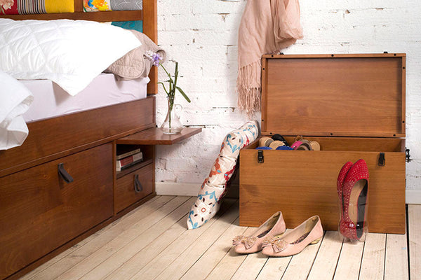 quarto com bau de madeira keep caramelo ao lado da cama com tampo aberto